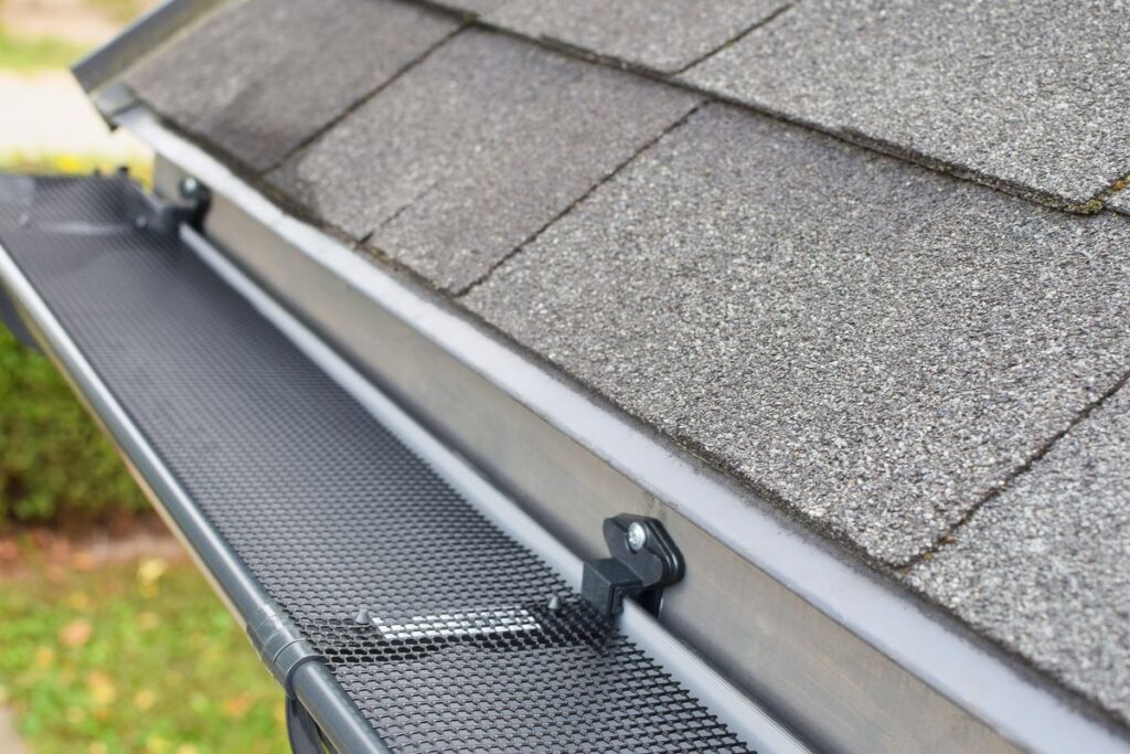 Shingled roof with gutter guard installed, designed to prevent debris accumulation. The mesh cover ensures efficient water drainage, preserving the roof's integrity.